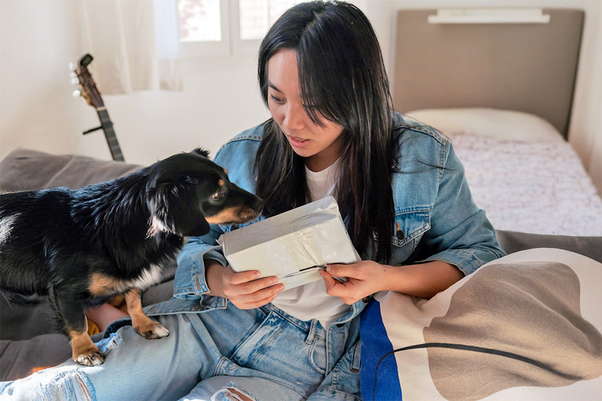 a dog looks at a package a woman is holding