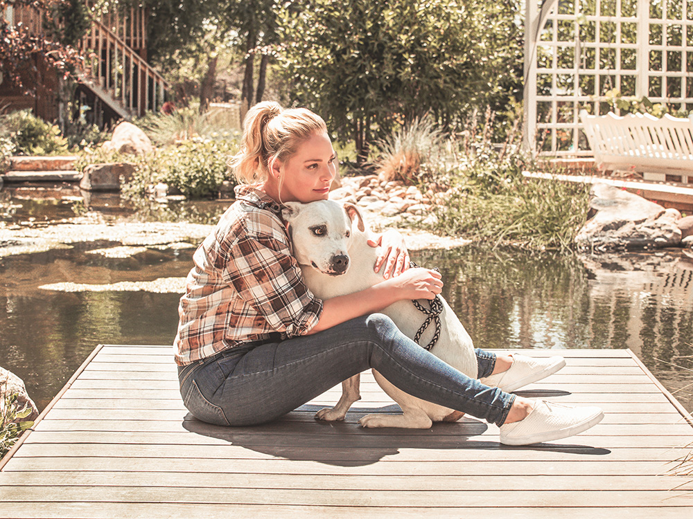 Katherine Heigl snuggles her dog on a dock.