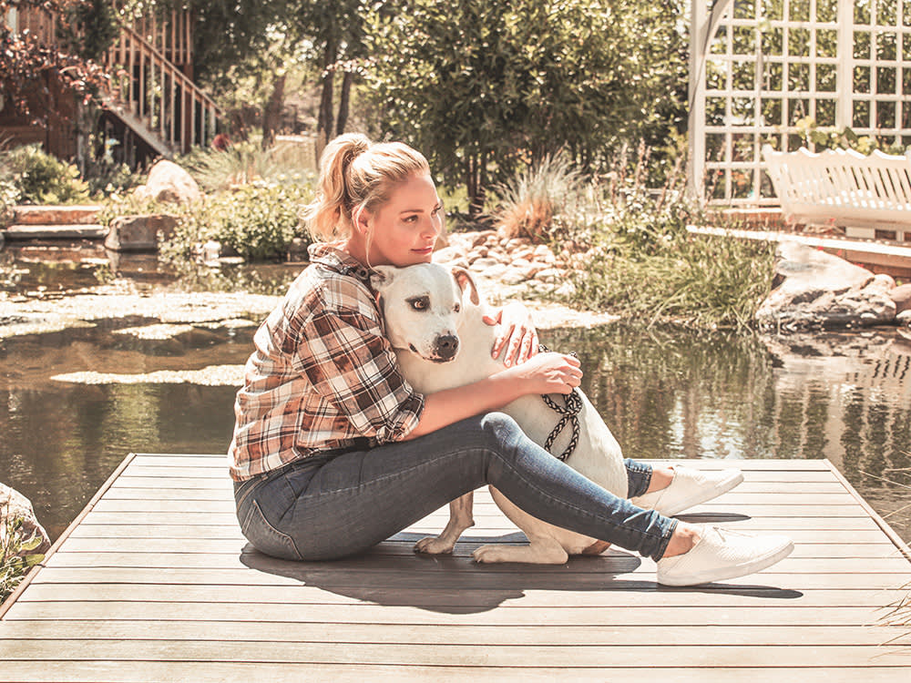 Katherine Heigl snuggles her dog on a dock.