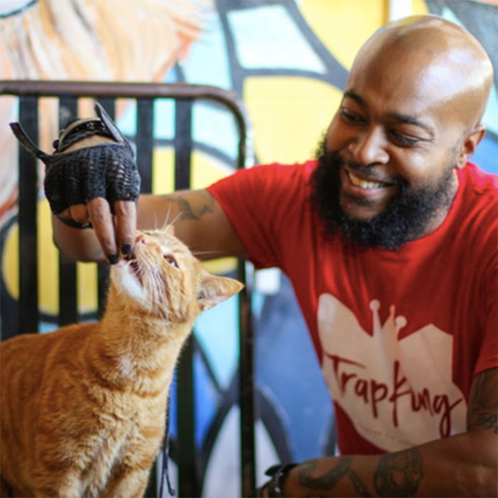 Sterling "Trapking" feeding a treat to an orange rescue cat