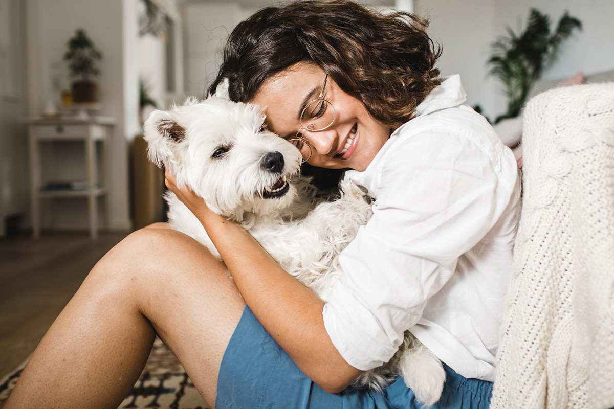 person cuddling a white dog