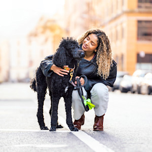 Woman hugs her black poodle dog outside in New York City.