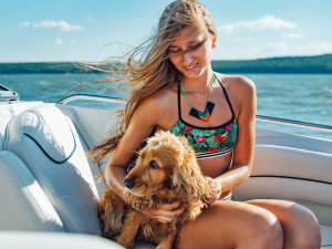 Woman and her brown dog on a boat in the sun.