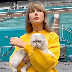 Taylor Swift holding a cat outside.