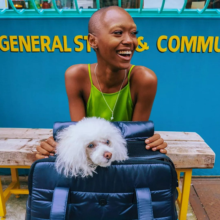 model holding white dog in black carrier