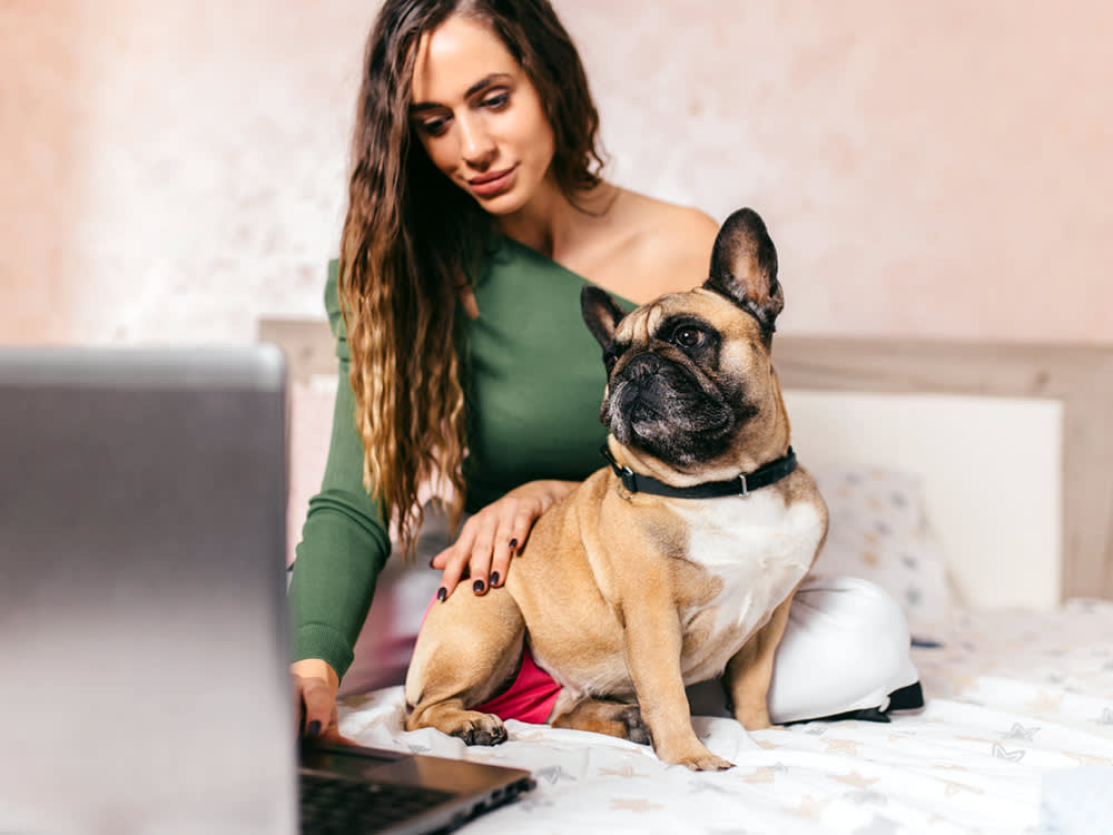 Woman with her French Bulldog at home on the bed.