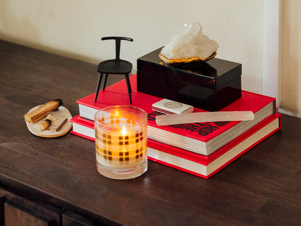 an incense tray, a candle, two red books piled, a small miniature chair and a crystal on top of the books