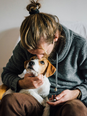 Man Kissing And Hugging a small white and brown dog.
