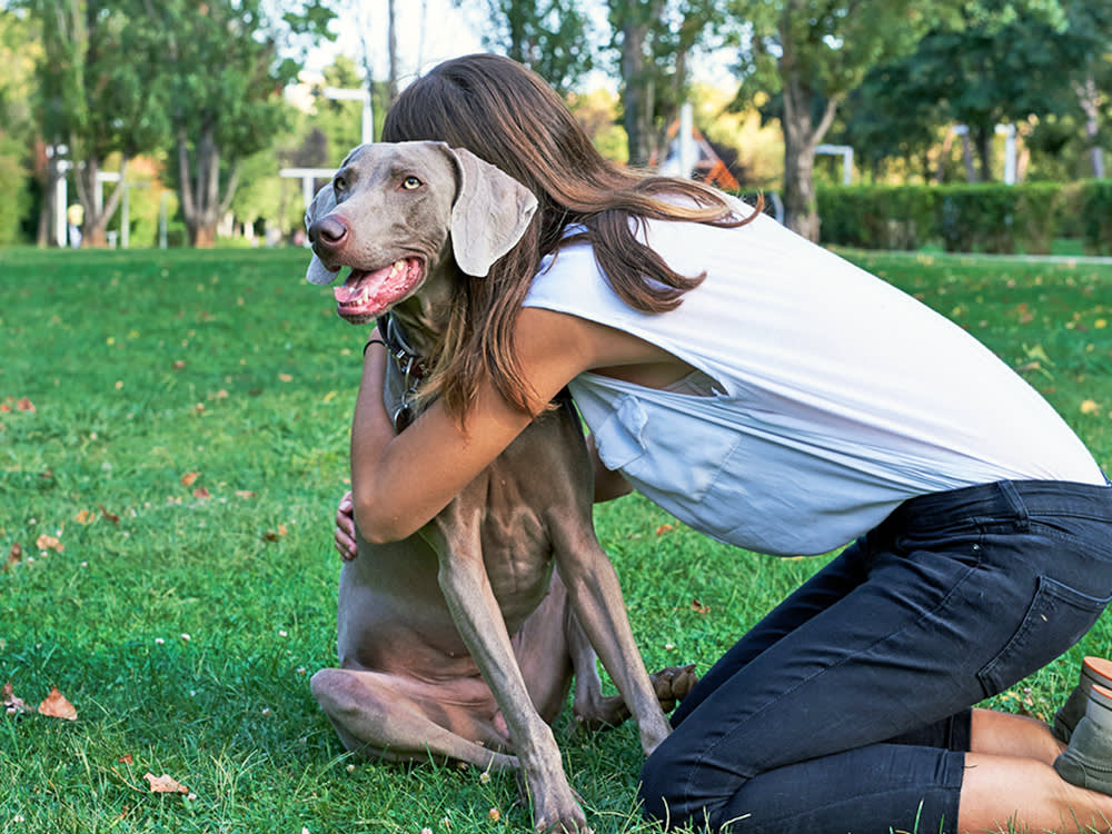 Woman hugging her dog outside.