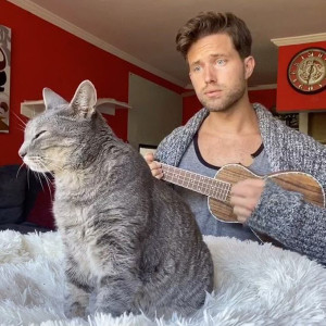 nathan the cat lady playing guitar to his cat