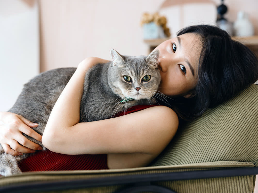 Woman hugging her cat at home.
