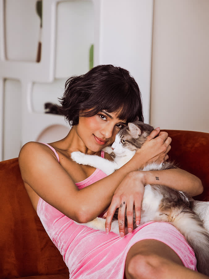 Aparna Brielle with her small cat on a couch