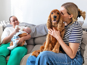 Two friends hanging out with their baby and dog at home.