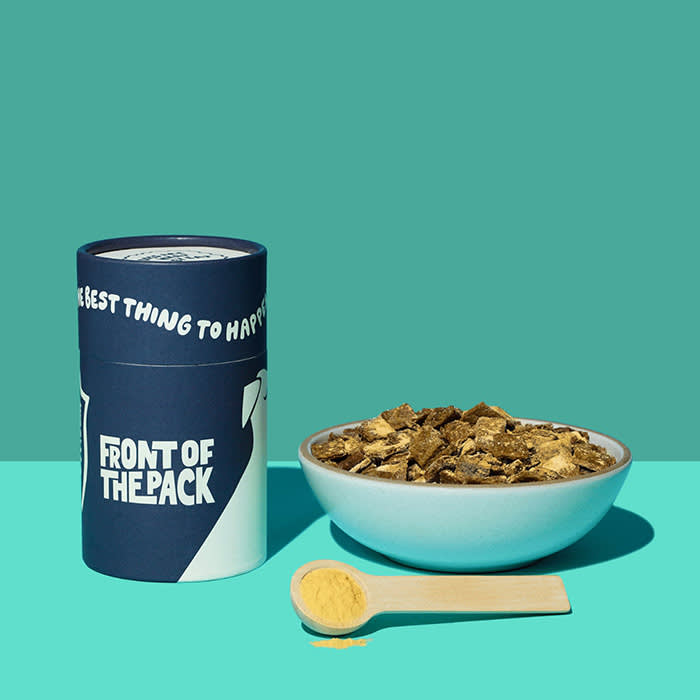 A bowl of dog food photographed alongside product packaging from the company, front of the pack. 
