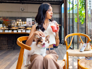 Woman at a cafe with her small fluffy dog.
