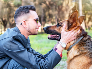 Man looking at her German Shepherd dog outside.