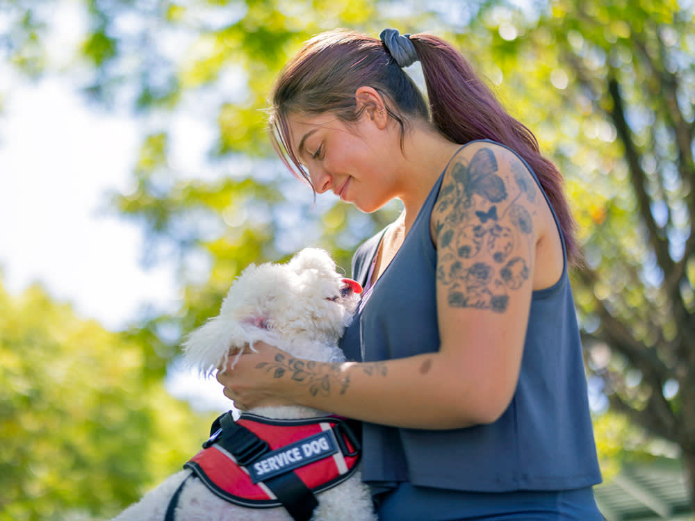 Woman petting her small service dog.