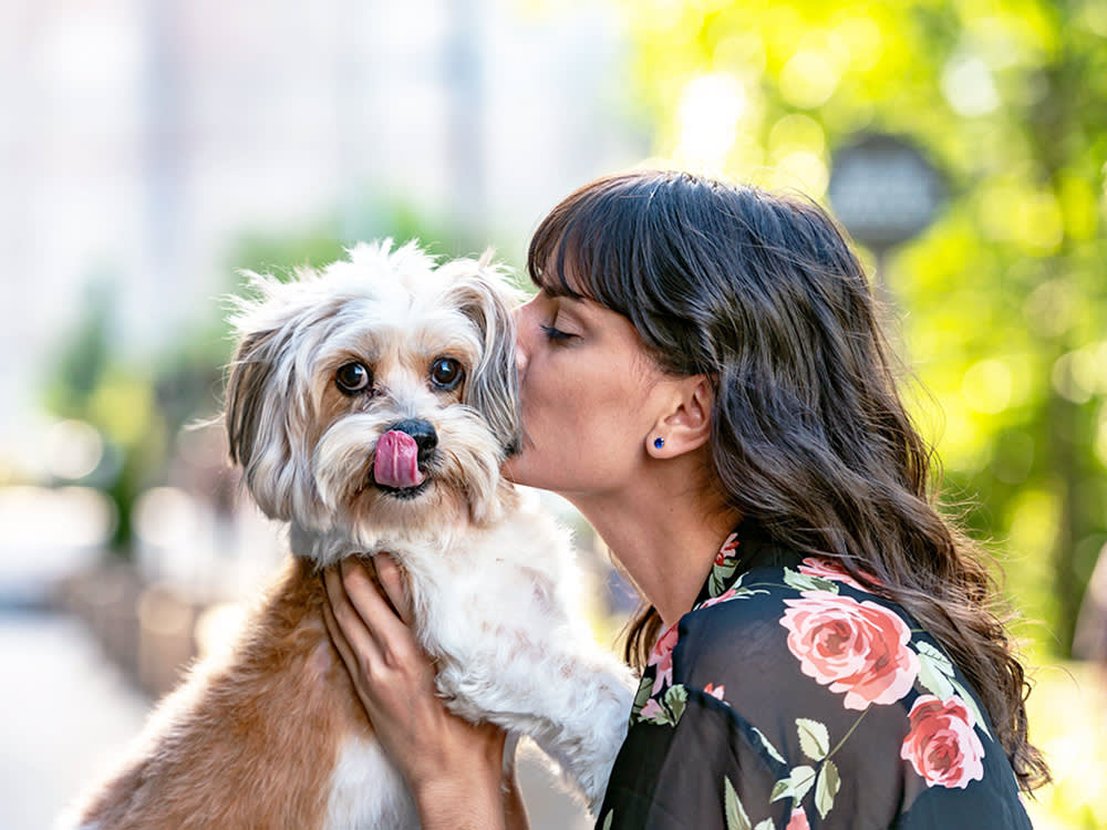 Woman kissing her dog outside in the city.