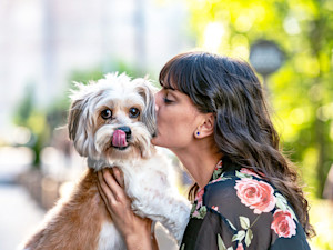 Woman kissing her dog outside in the city.