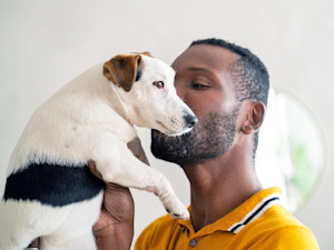 Man holding his dog at home.