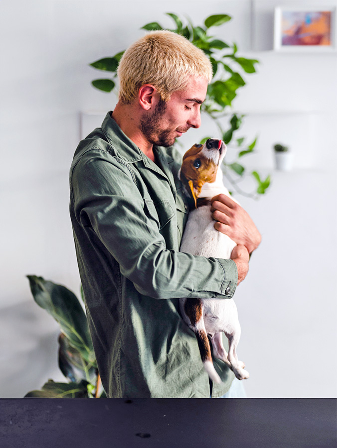 Man hugging his small dog at home.