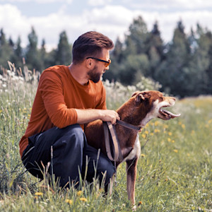 Man sitting outside with his dog in a field.