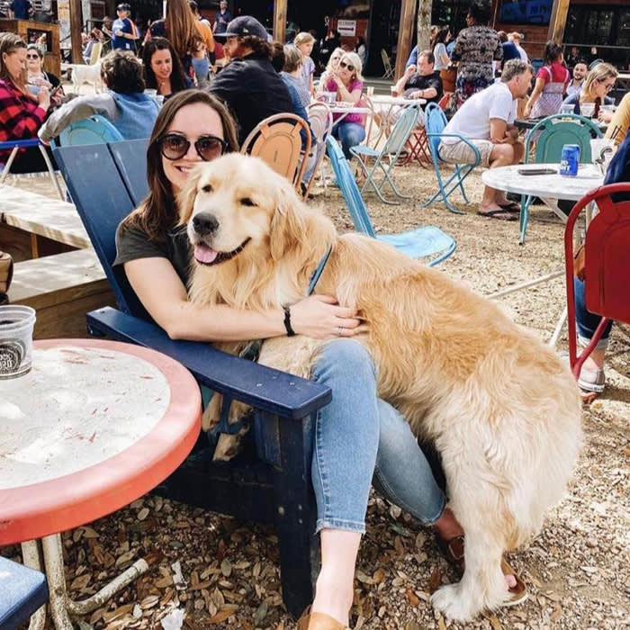 a large yellow dog sitting on a person outdoors at Truck Yard