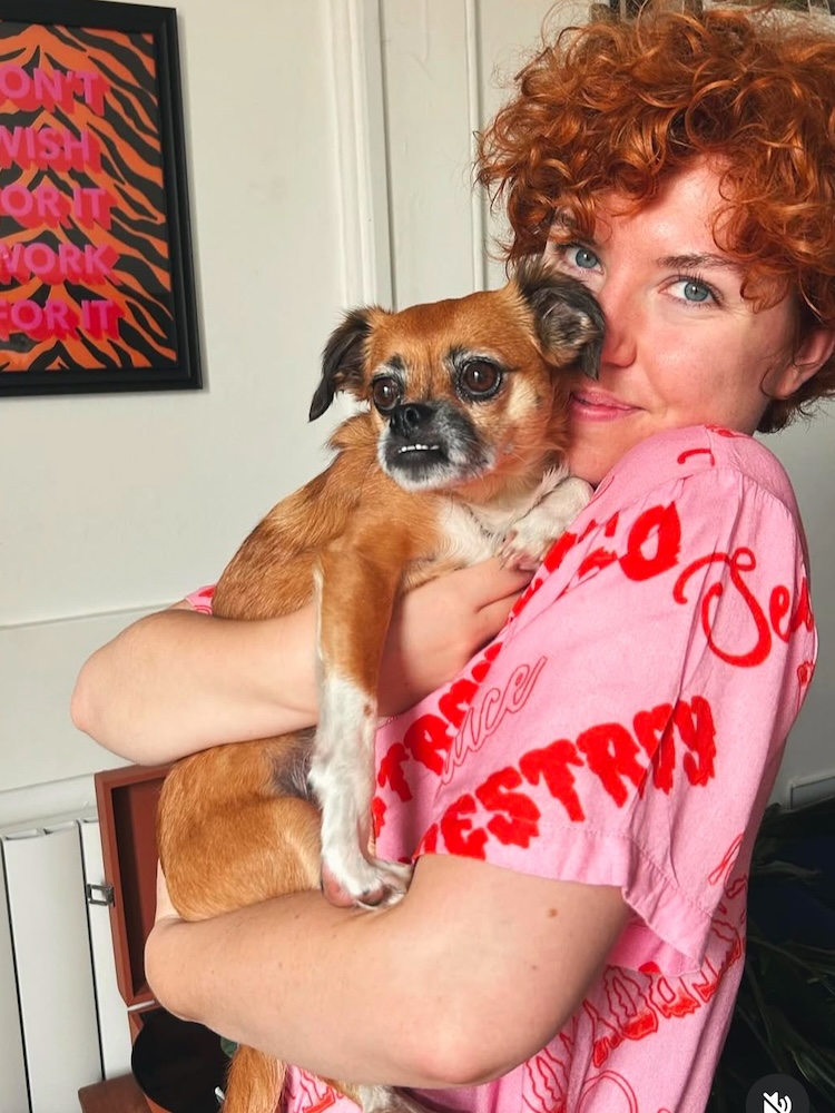 a woman with red hair holds a little dog