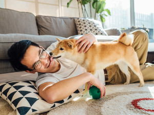 A man is lying on the ground with his dog licking his face.