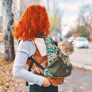 Woman wearing a sling with a cat inside.