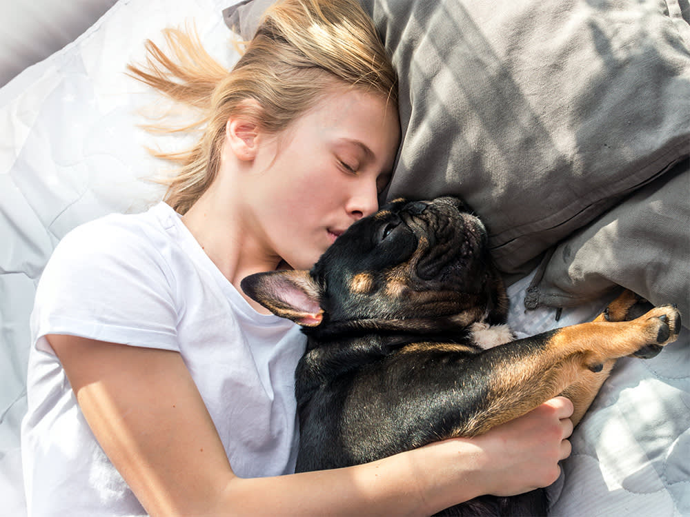 Girl sleeping with her French Bulldog dog in bed.
