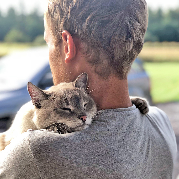 Man holding cat outside in his arms.