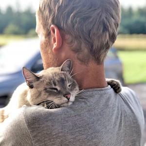 Man holding cat outside in his arms.