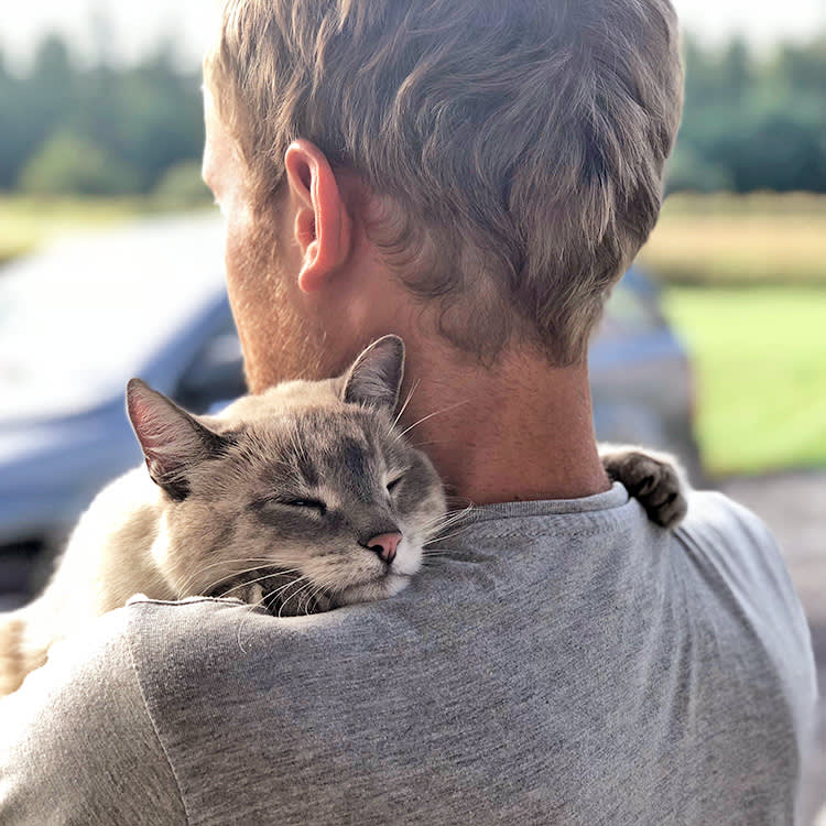 Man holding cat outside in his arms.
