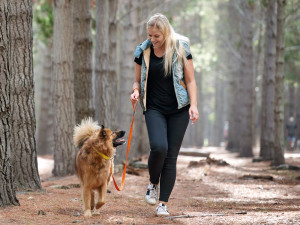 Woman taking her dog on a walk through the woods.