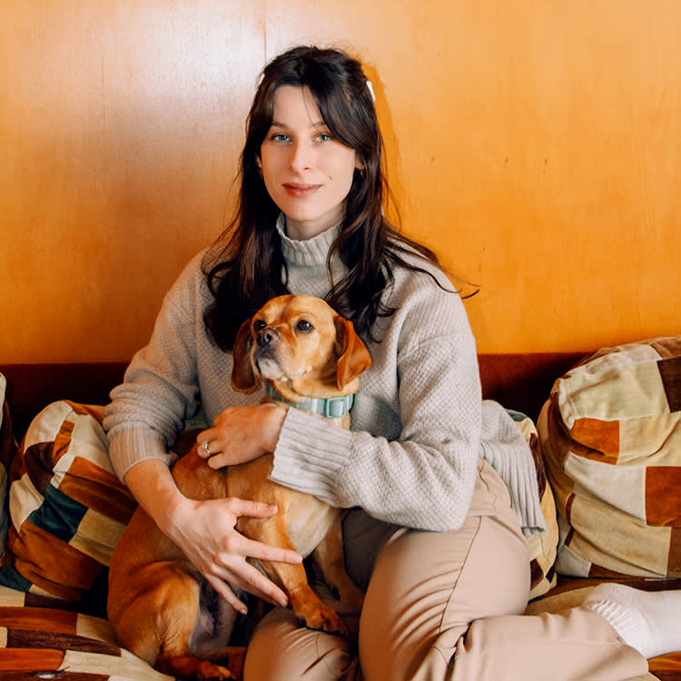 Sasha Spielberg sits with her small orange dog