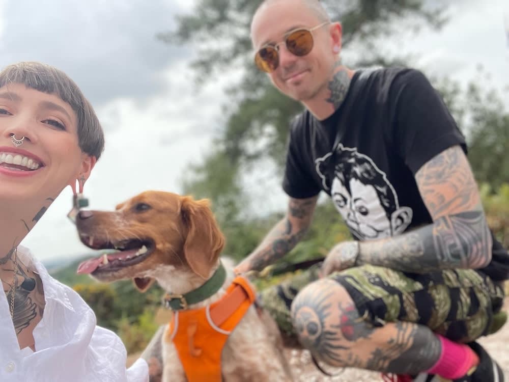 a man and a woman with tattoos huge a red and white dog
