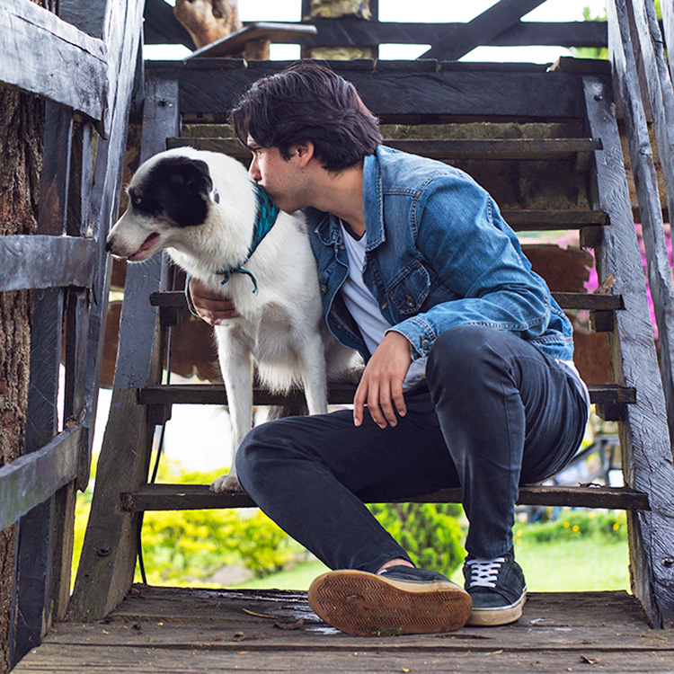 Man holding her large dog outside.