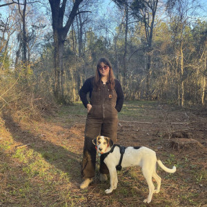 A woman in the woods with her dog. 