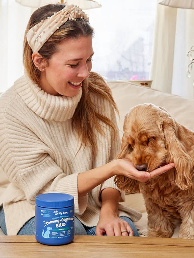 Woman feeding her dog a supplement at home.