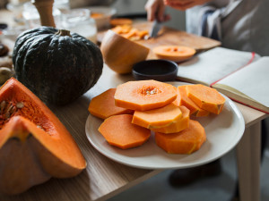 Close up of chopped pumpkin with person chopping pumpkin in the back