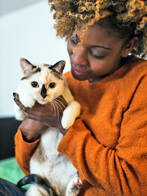Woman holding her cat in her arms at home.