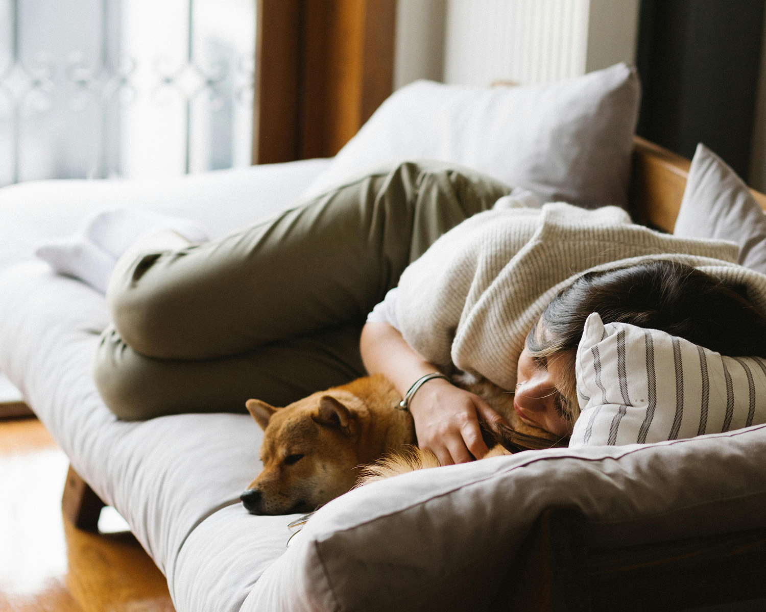 Woman in Knit Shirt Lying on Bed beside a Brown Dog
