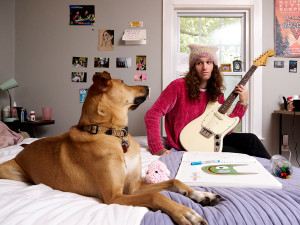 Briston Maroney holding a guitar and looking at his dog