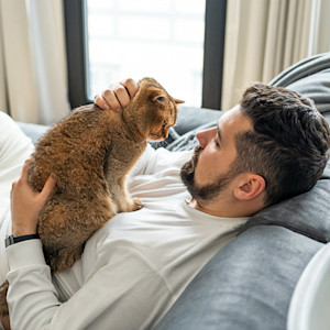 Man petting his cat at home.