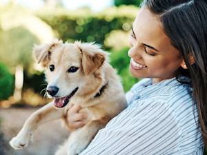 woman snuggling puppy while holding them