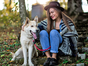 Woman petting her pet wolf dog outside.