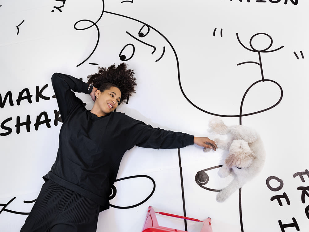Artist, Shantell Martin laying on the floor with her dog in her studio. 