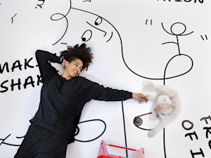 Artist, Shantell Martin laying on the floor with her dog in her studio.
