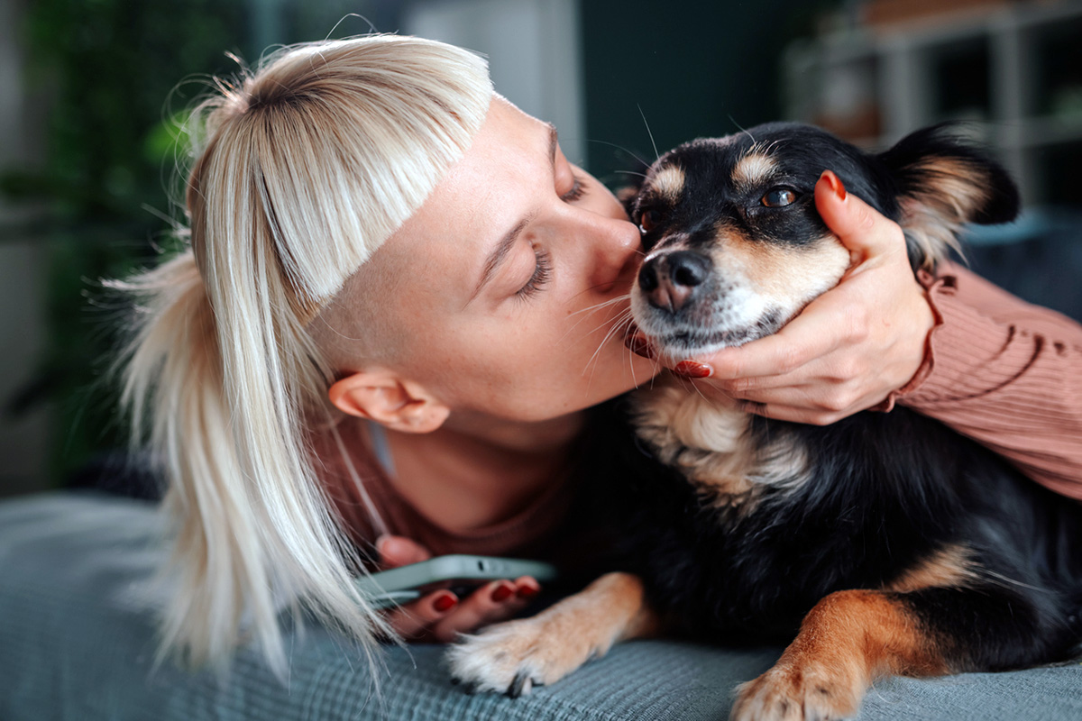person kisses her dog on the side of the face